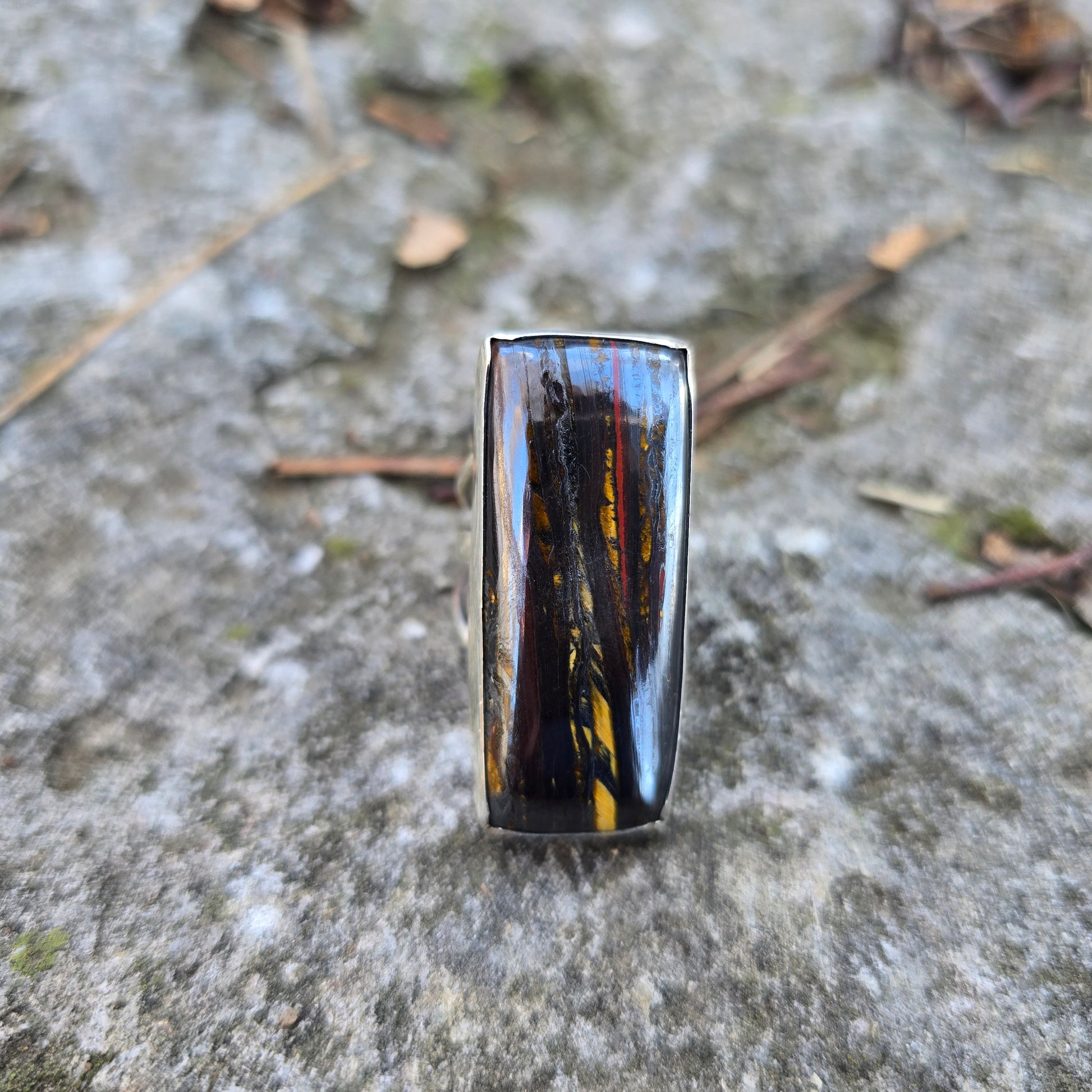 brown tiger iron rectangle stone ring displayed on rock