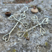 Load image into Gallery viewer, silver cross heart dangle earrings displayed on mossy rock
