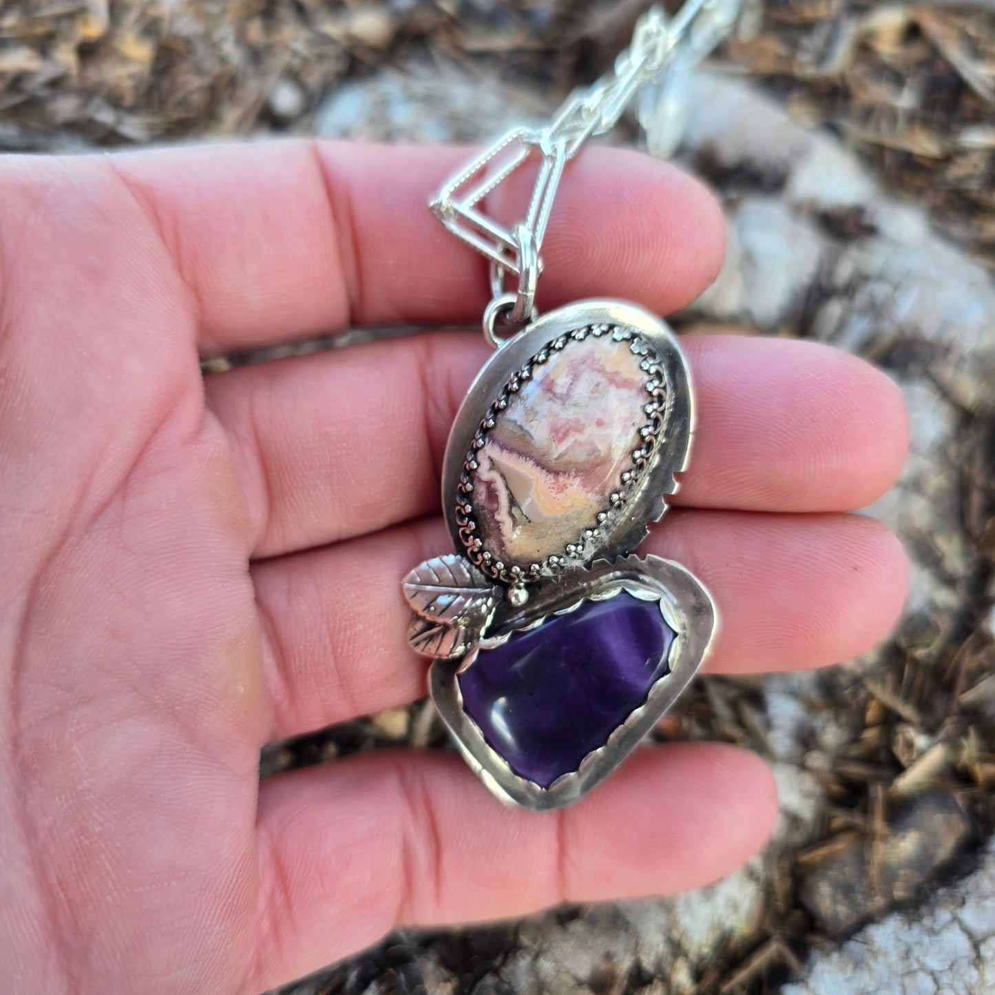 sterling silver leaf with pink and purple stone pendant displayed on hand