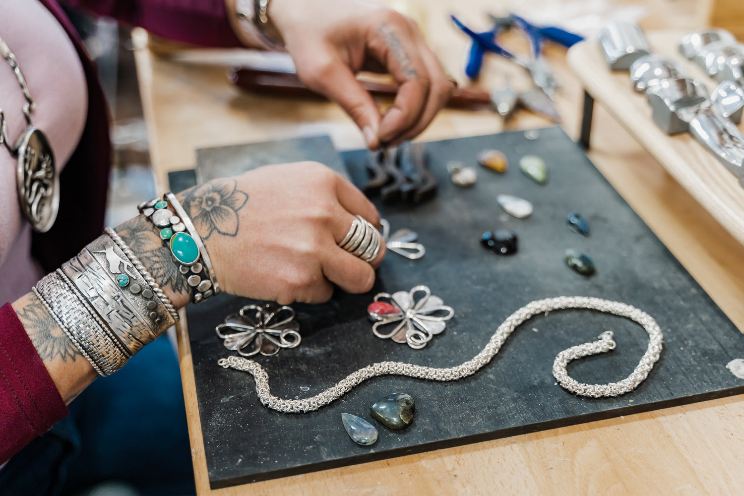 Silversmith working on sterling silver jewelry at workbench detailed view.