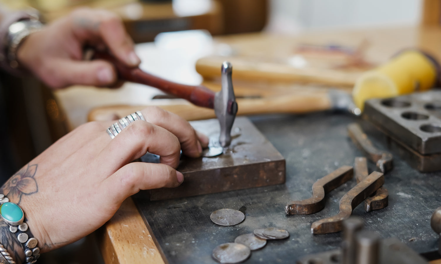 Silversmith using traditional hammer and anvil to hand-forger sterling silver jewelry in Adirondack Foothills Studio.