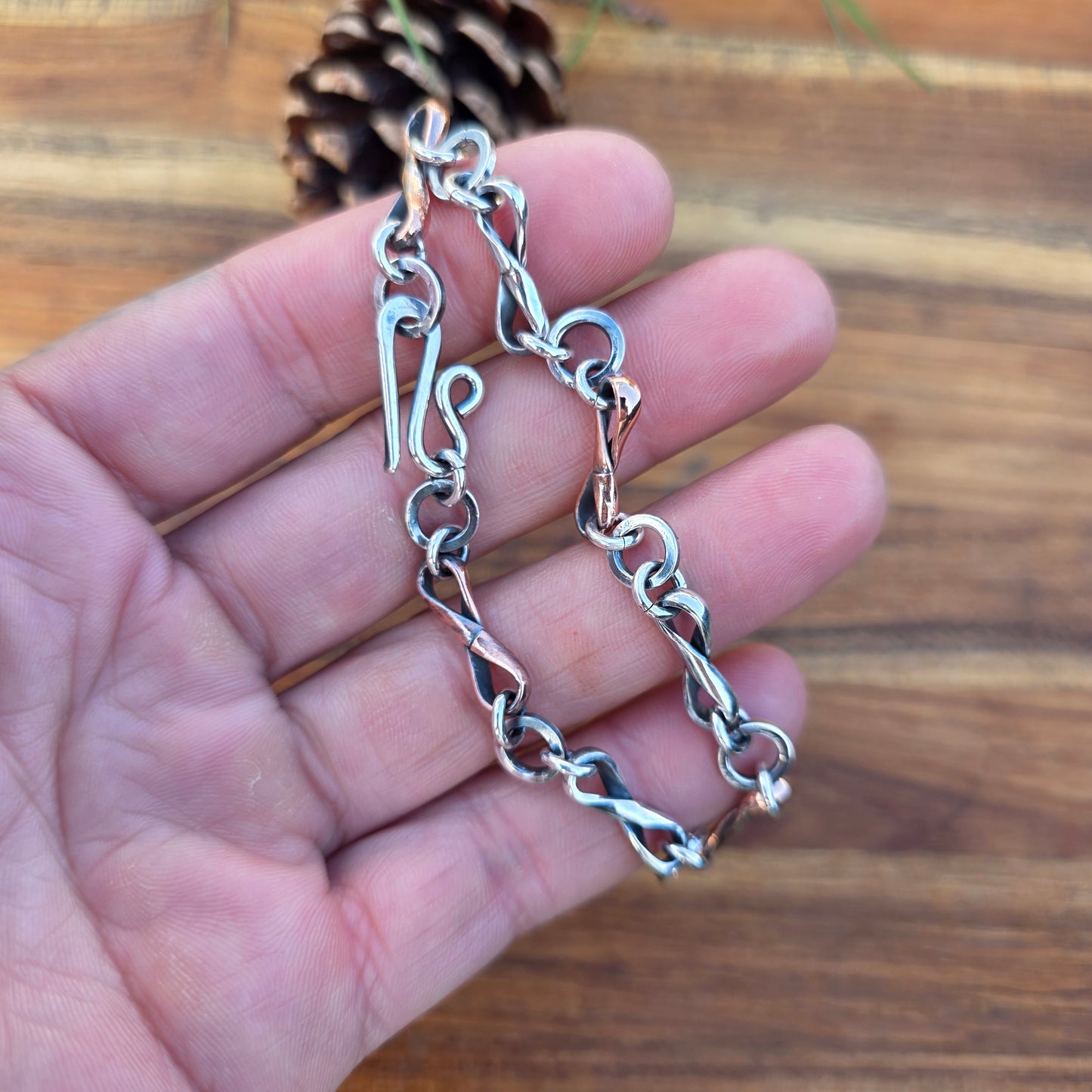 Infinity link bracelet featuring alternating copper and sterling silver half round wire links, oxidized for contrast, photographed with its clasp in on hand top view
