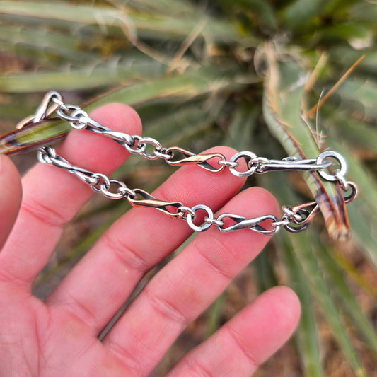 Infinity link bracelet featuring alternating copper and sterling silver half round wire links, oxidized for contrast, photographed with its clasp in a natural environment.