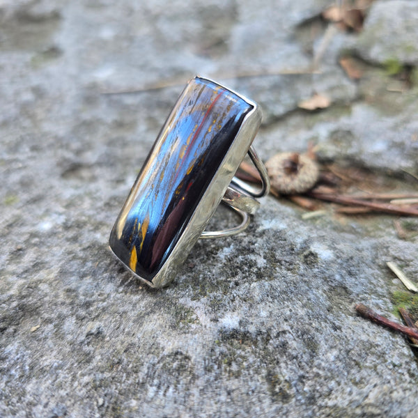 sterling silver and brown tiger iron stone ring displayed on rock side angle