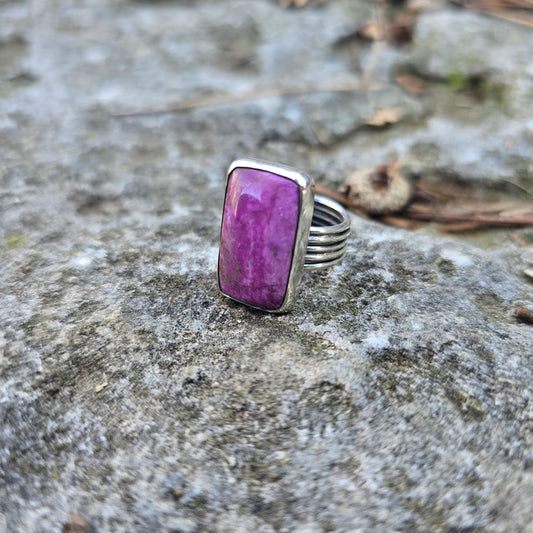 silver triple shank ring with pink cobalto stone displayed on rock