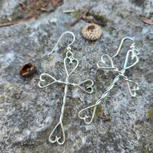 Load image into Gallery viewer, silver heart and cross earrings displayed on mossy rock
