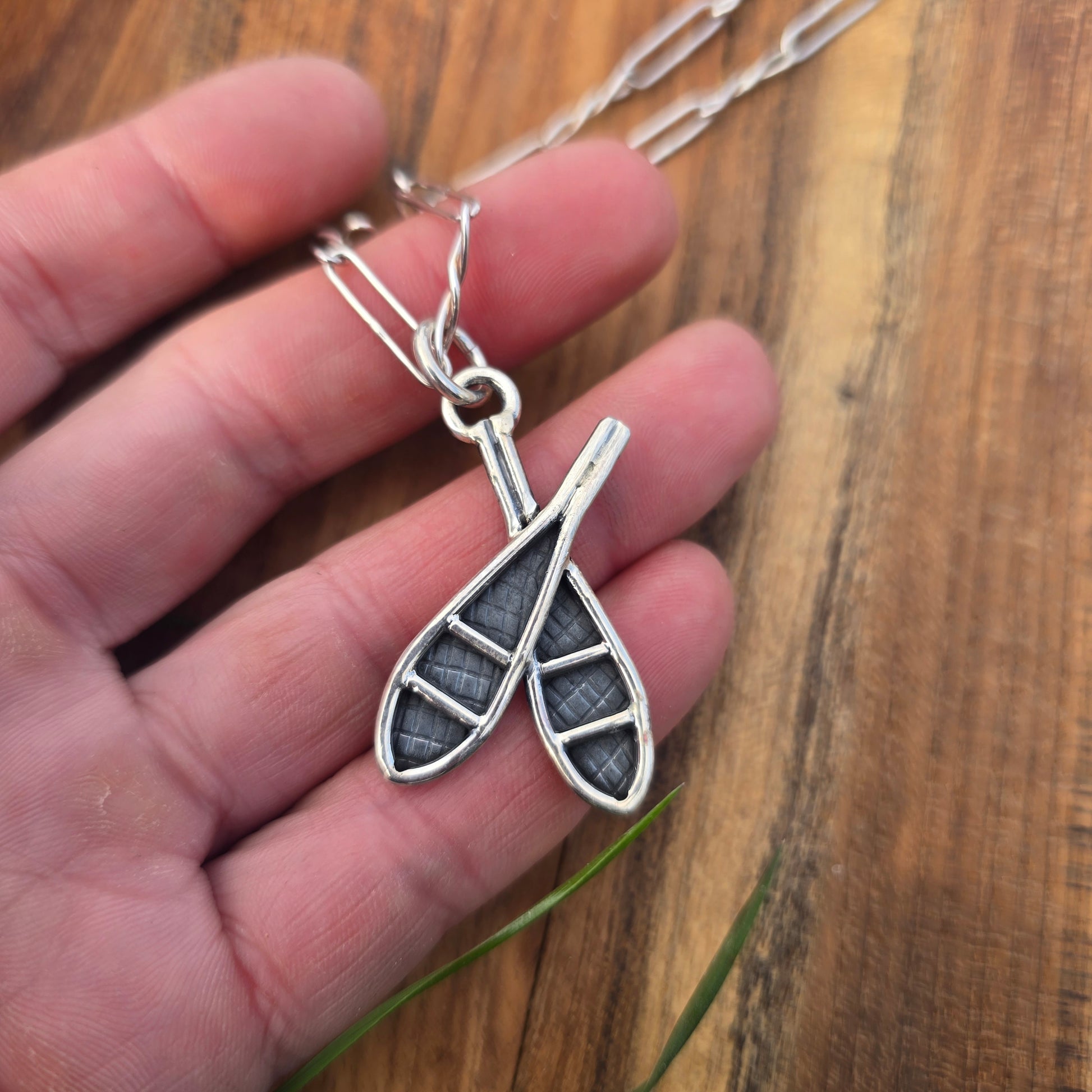 sterling double snowshoe pendant displayed on hand