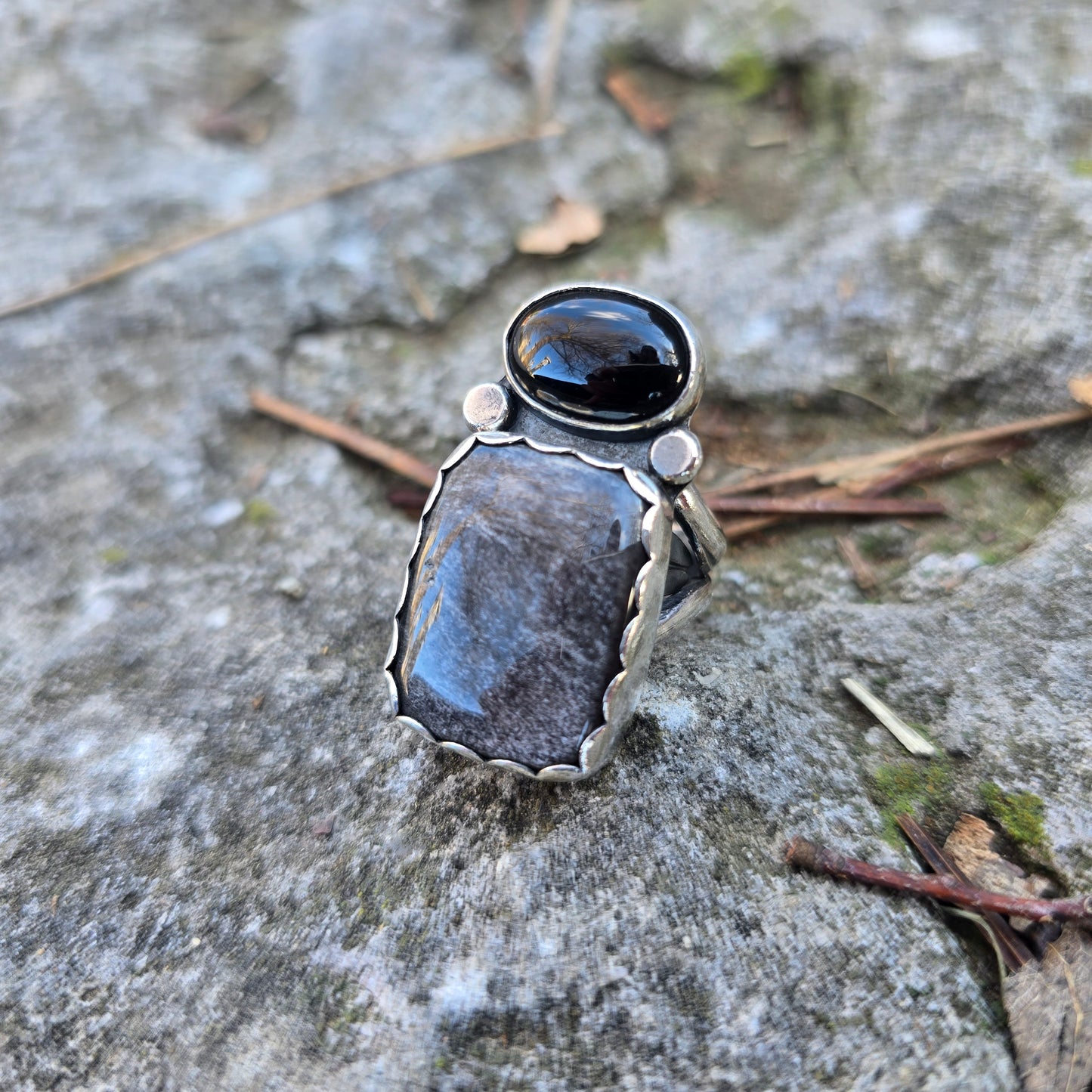 sterling silver black onyx and obsidian ring displayed on rock