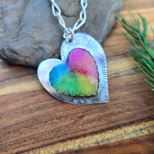 Angled top view of a heart-shaped sterling silver rainbow quartz pendant showing thickness and surface finish.