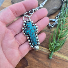 Load image into Gallery viewer, On-hand view of a sterling silver turquoise cross pendant showing scale, thickness, and beaded structure.
