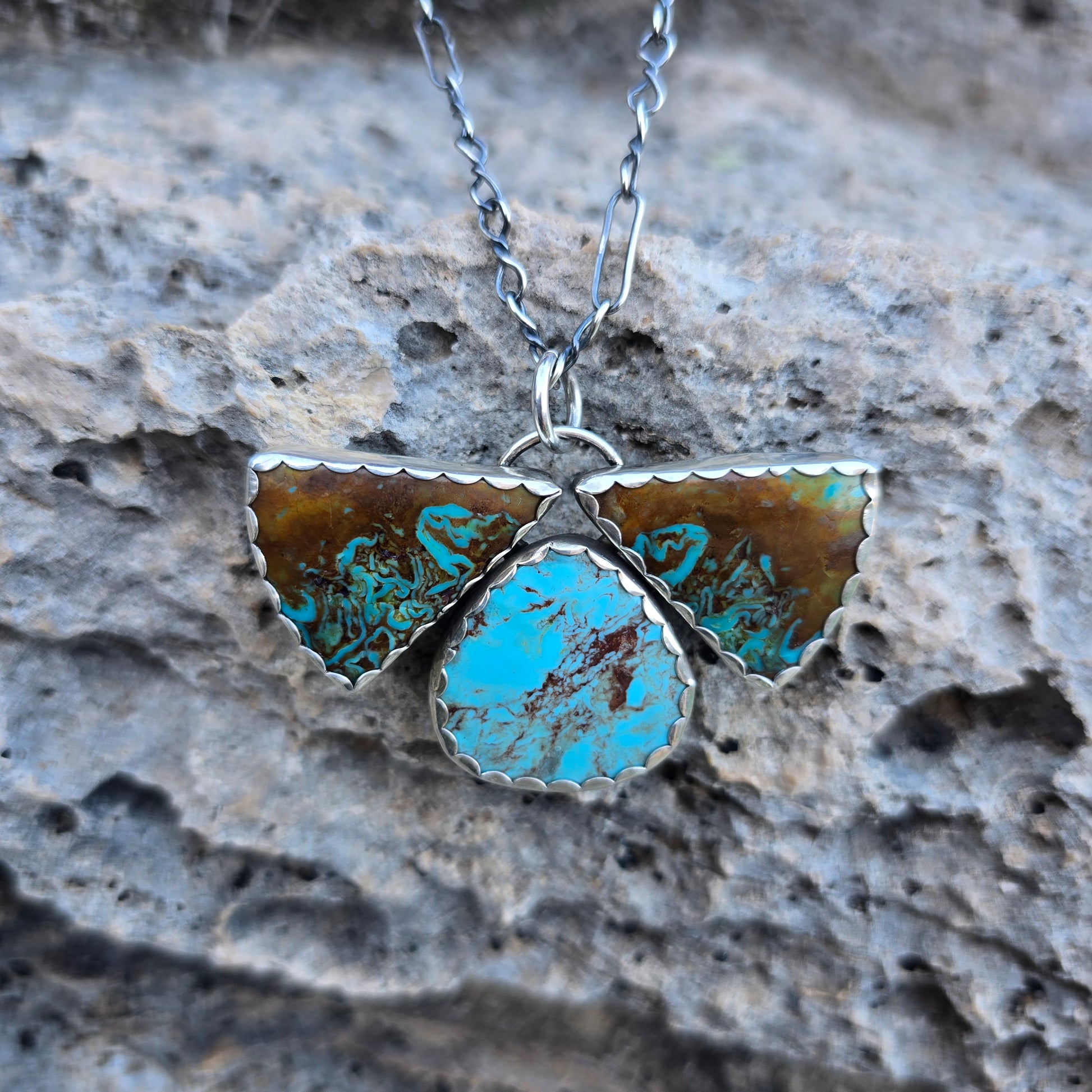 Patagonia turquoise three stone pendant with scalloped bezel detail, featuring two triangular stones and one oval stone with blue and brown matrix.