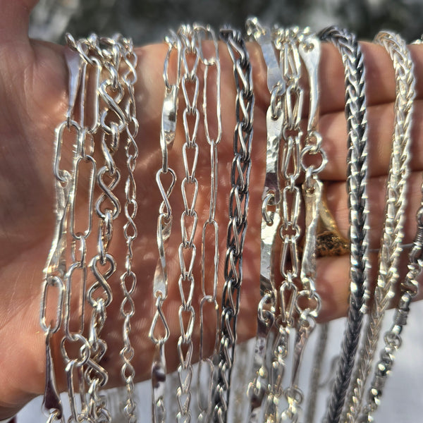 collection of sterling silver shiny and oxidized chains shown on hand front view