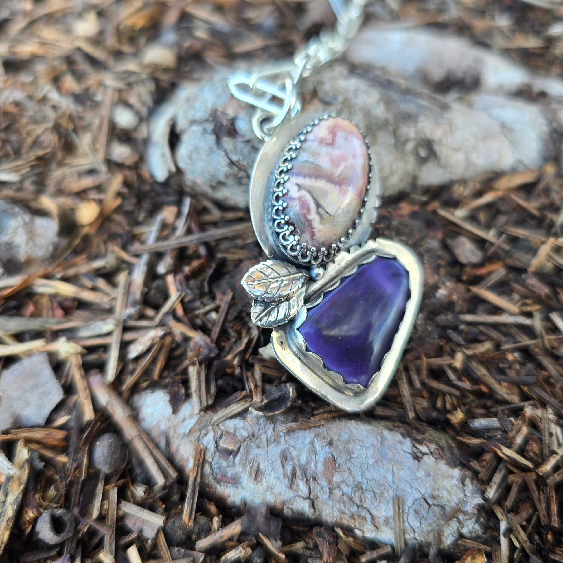silver leaf pendant with purple jasper and agate displayed on ground with rocks