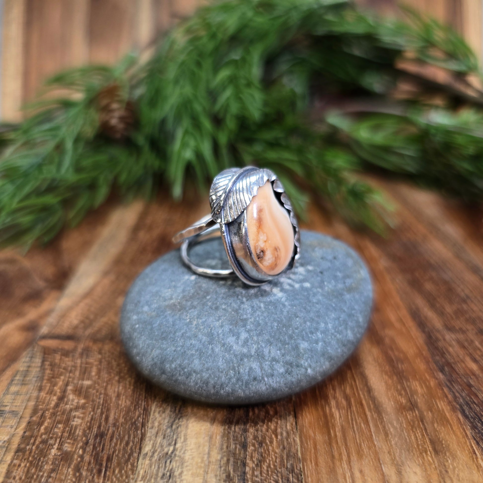  angled view of sterling silver feather-wrapped ring featuring an elk ivory setting