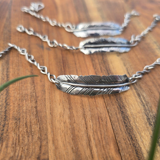 Sterling silver feather-shaped bracelet on a wooden surface