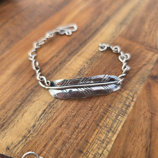 Silver feather bracelet on a wooden surface