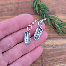 Load image into Gallery viewer, front view of 1.5 inch sterling silver feather earrings displayed on hand
