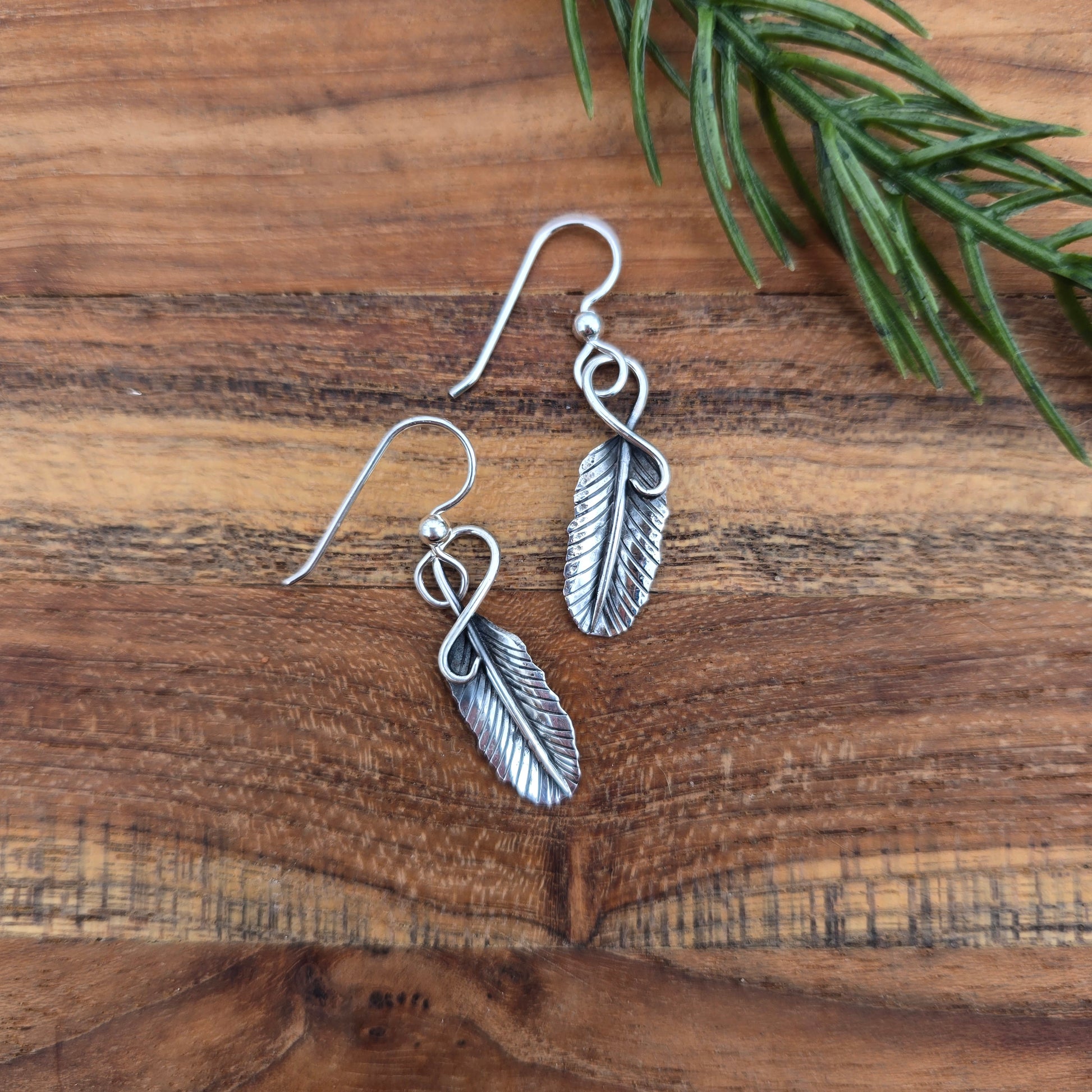 top view of sterling silver feather earrings measuring about 1.5 inches