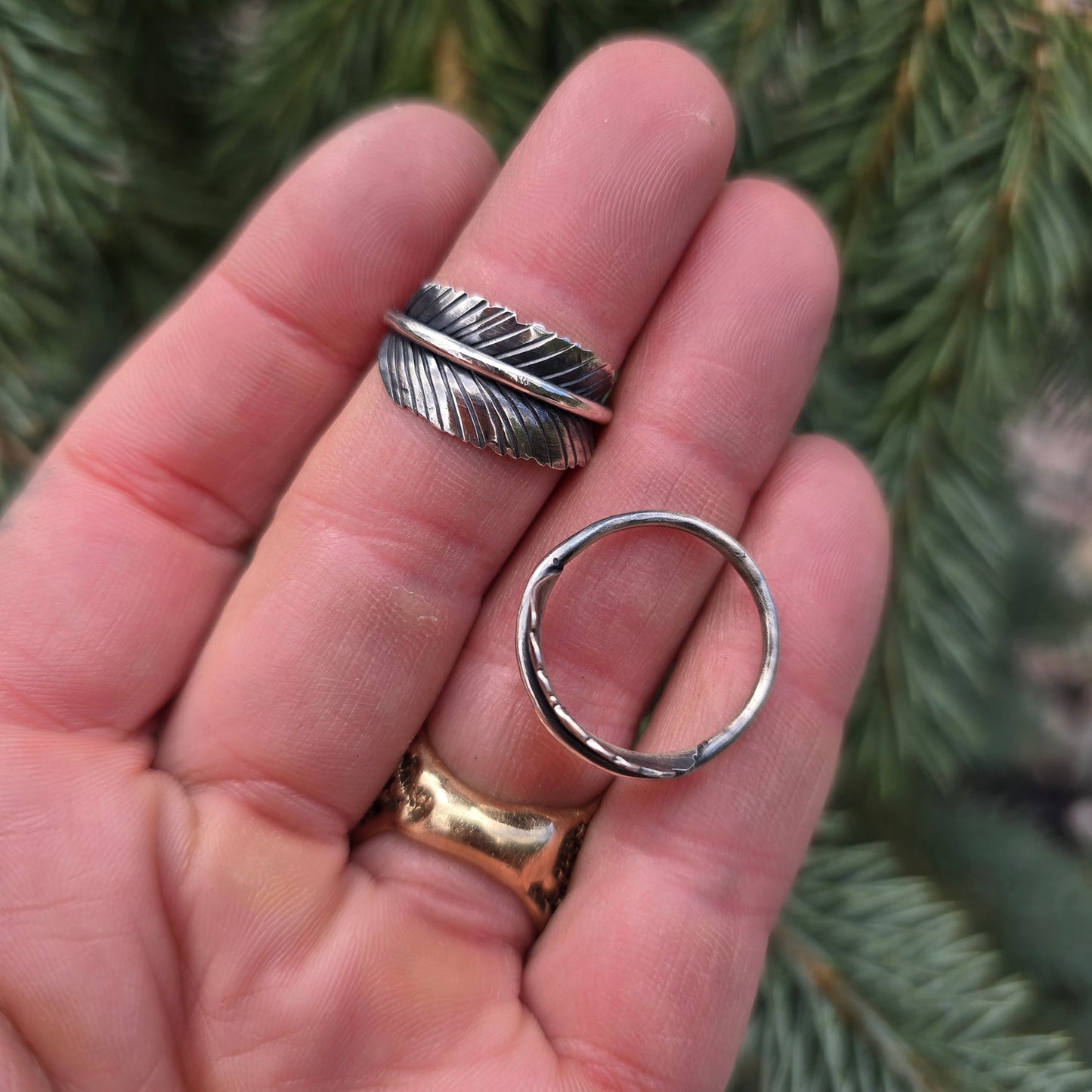 Hand-forged sterling silver feather ring displayed on hand