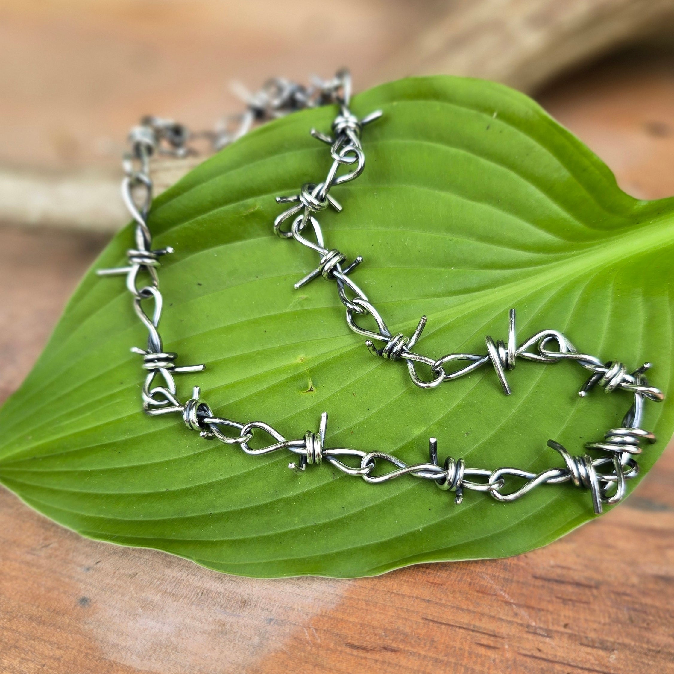 Hand-forged barbed wire sterling silver chain displayed top view.