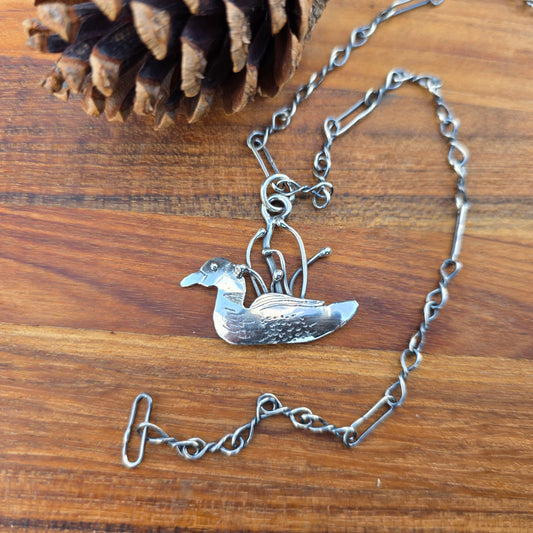 Sterling silver Adirondack loon pendant on chain displayed on wooden background