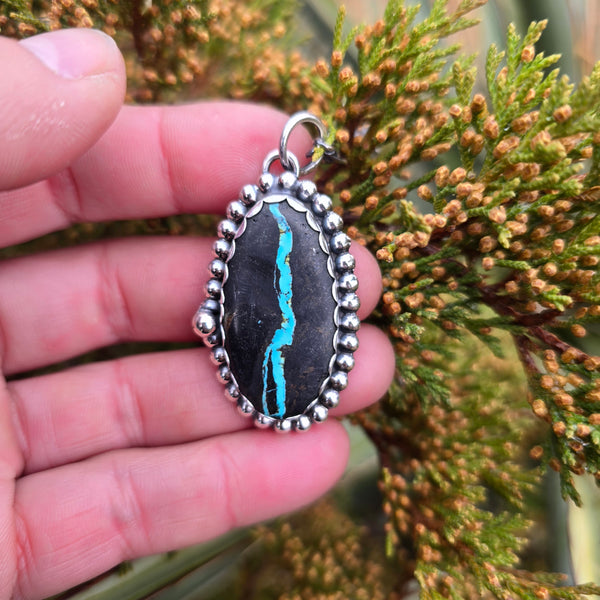 Sterling and Royston Ribbon turquoise pendant displayed in hand with natural background