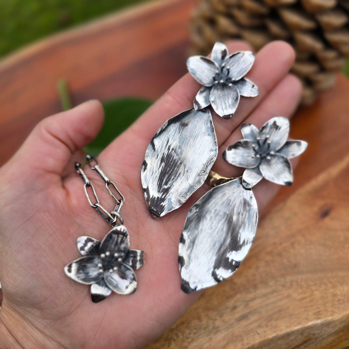 sterling silver trillium pendant, three-trillium necklace, and trillium earrings displayed together