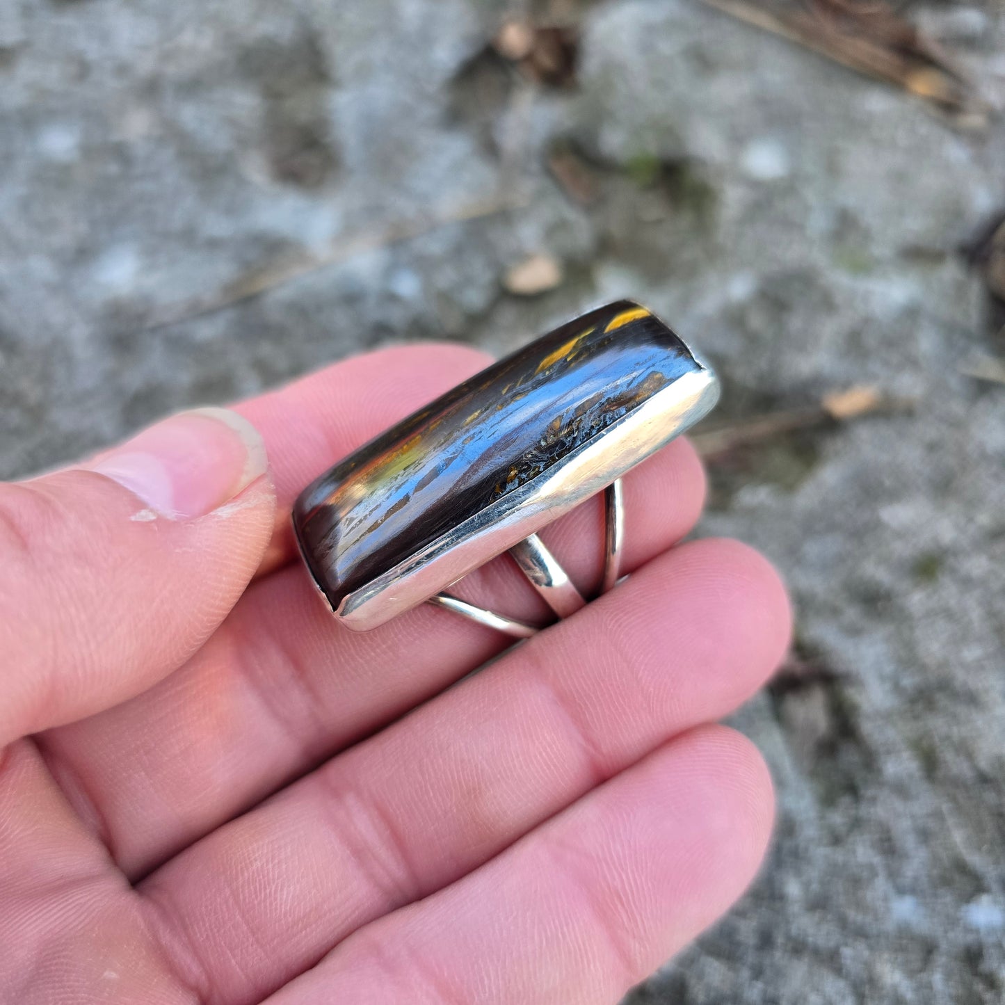 sterling ring with tiger iron cabochon displayed on hand side angle
