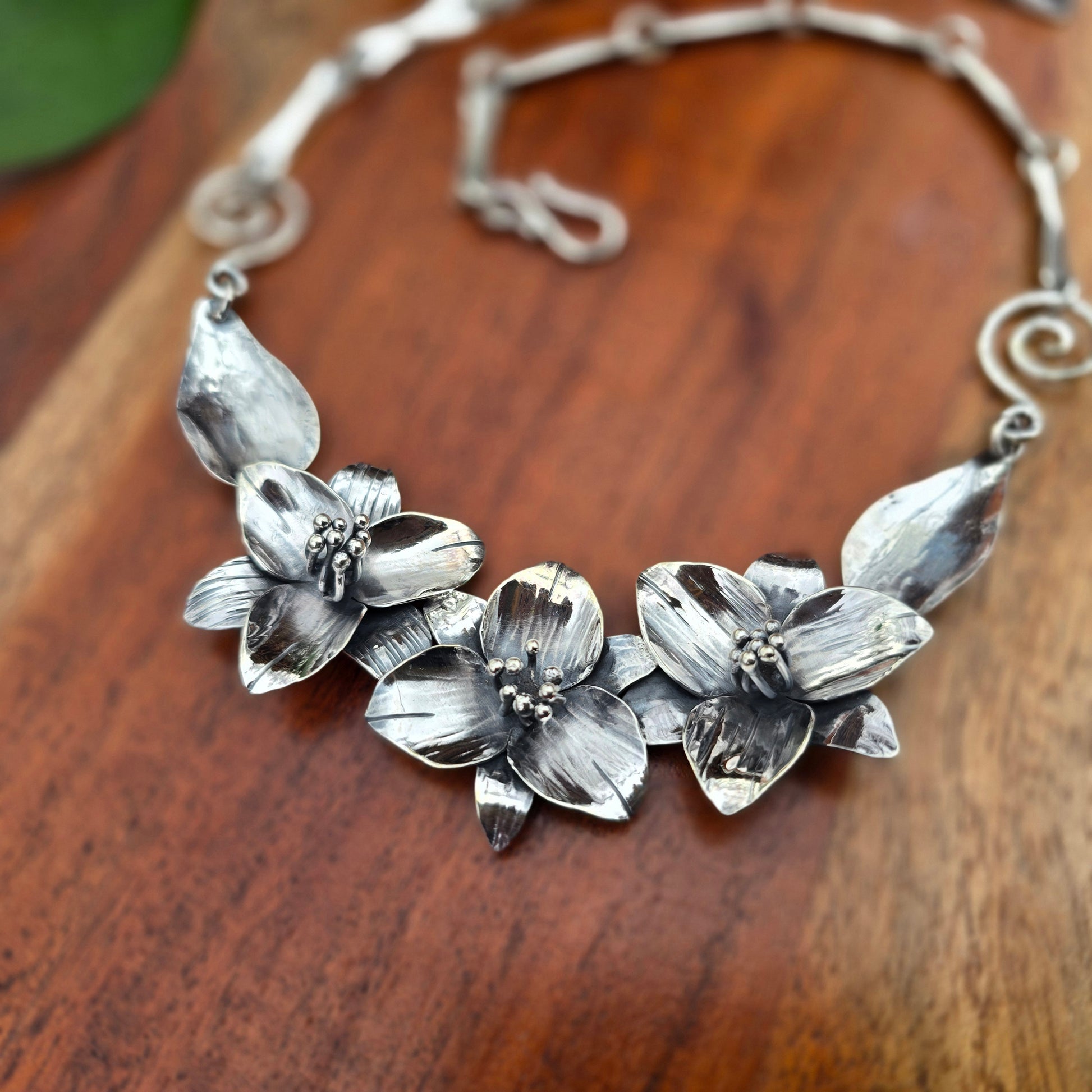 sterling silver necklace with three trillium flowers, leaf links, and heavy chain back angled view