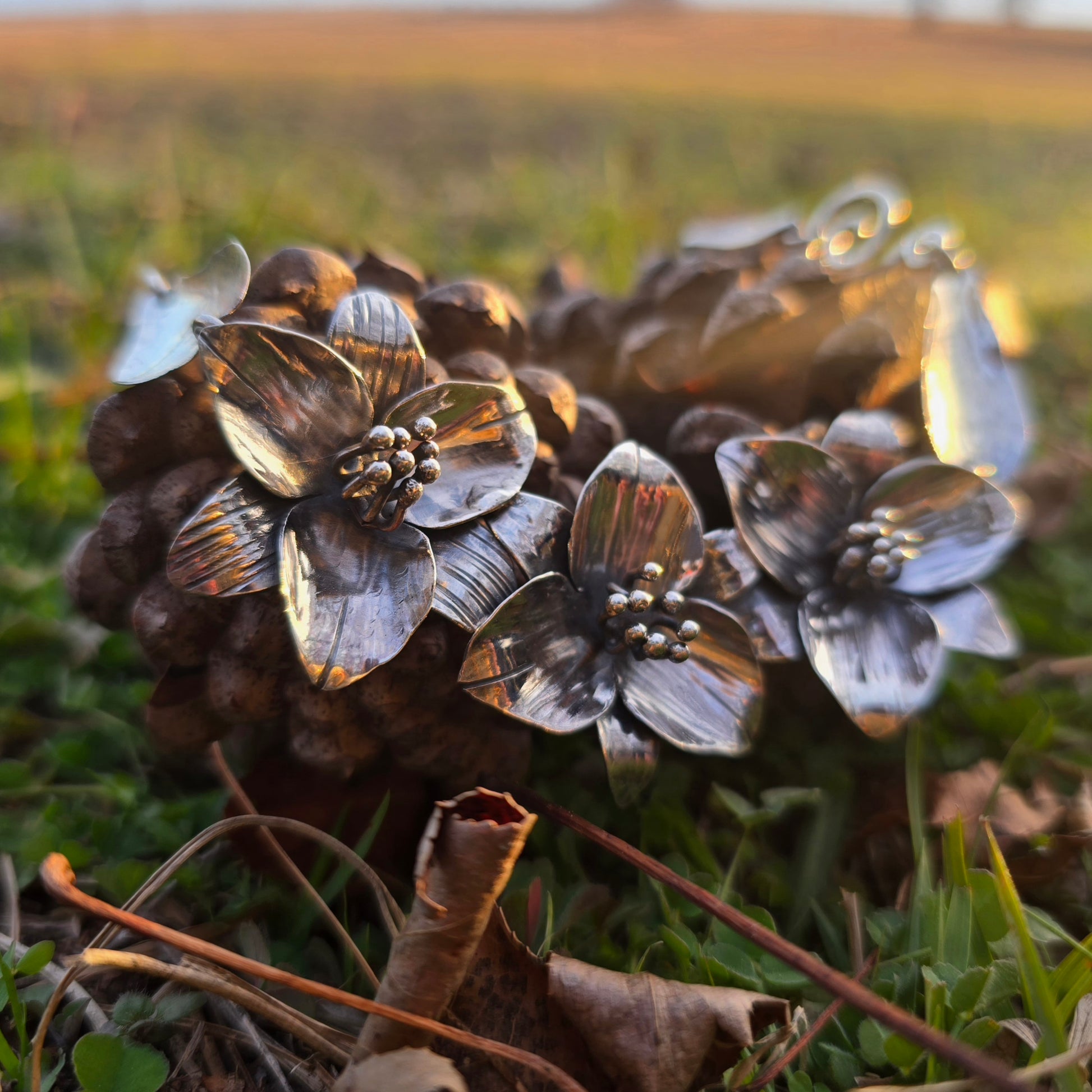 silver trillium necklace displayed on pinecones