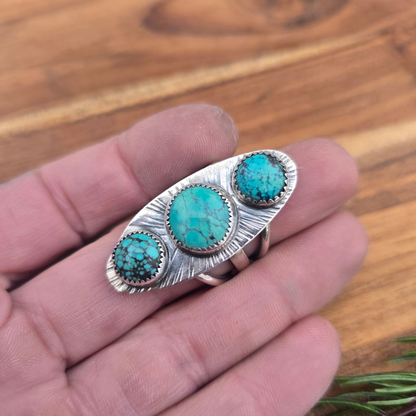 Detail of turquoise stones set in sterling silver statement ring displayed on hand