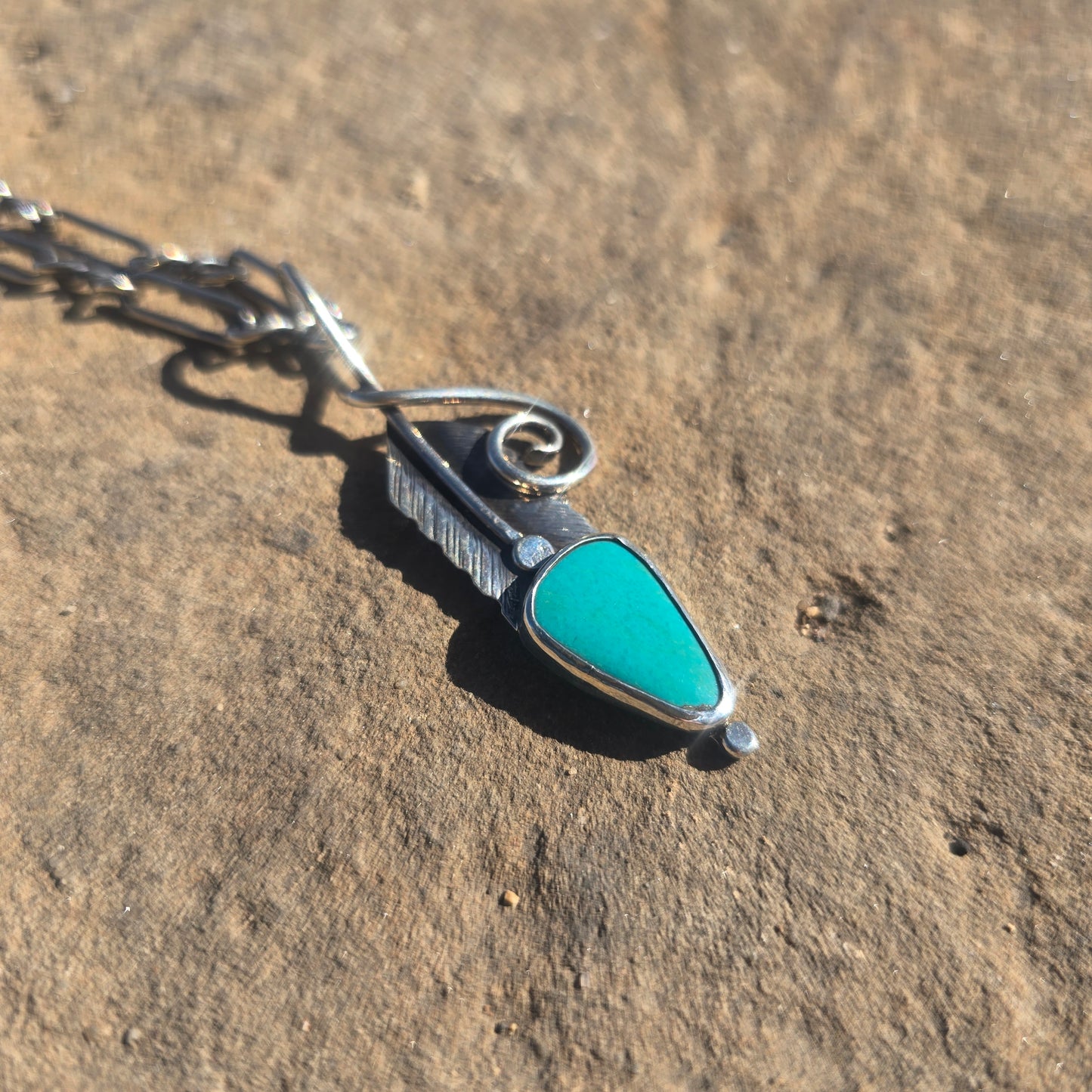 Sterling silver feather-shaped pendant with stamped surface detail