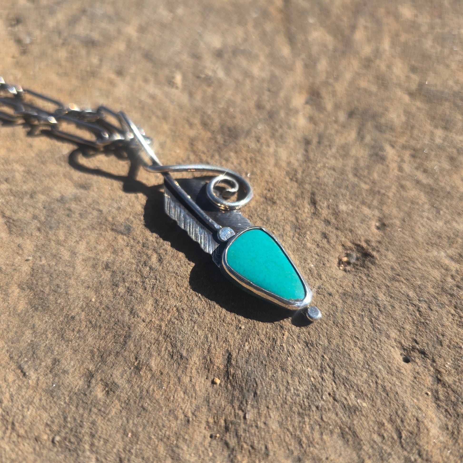 Sterling silver feather-shaped pendant with stamped surface detail