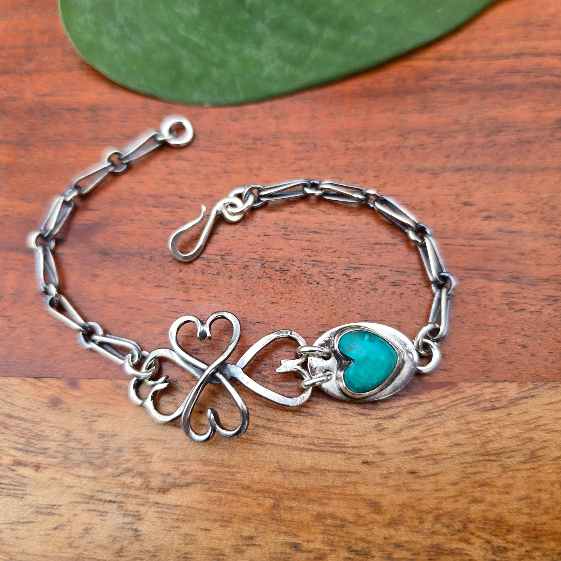 turquoise heart bracelet with twisted cross-heart sterling silver links displayed on surface