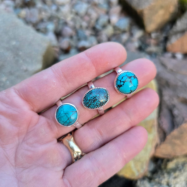 three turquoise rings with minimal bezel and sterling silver band worn on hand