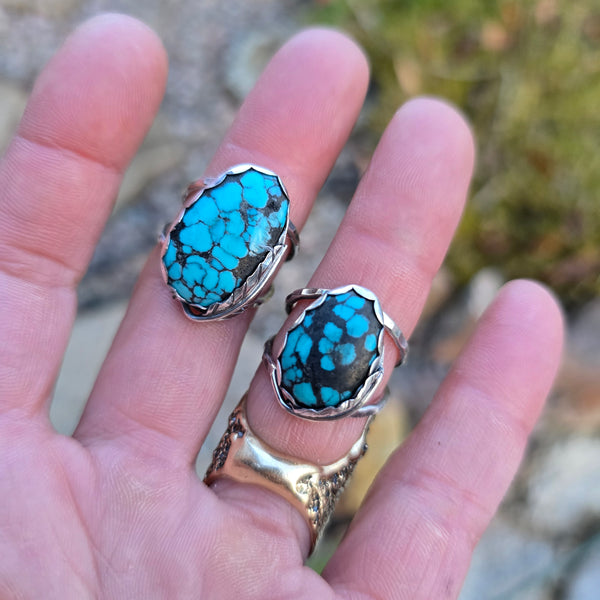 close-up of turquoise stones and feather wrap details on double shank rings on hand