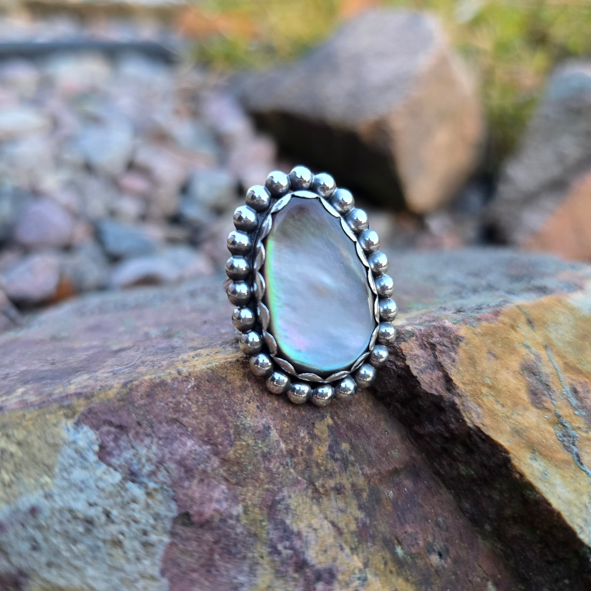 Close-up of a sterling silver ring featuring a luminous Mother of Pearl stone and bead-wire frame