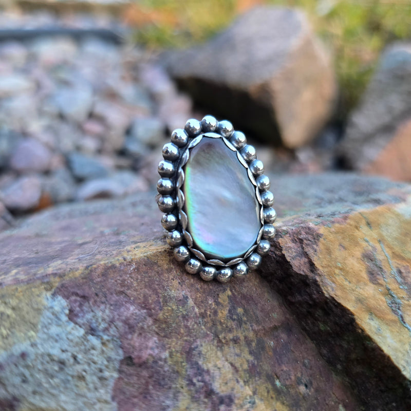 Close-up of a sterling silver ring featuring a luminous Mother of Pearl stone and bead-wire frame